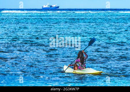 Colorato Native Woman Canoing snorkeling Cargo Ship Outer Reef Blue Water Moorea Tahiti Polinesia Francese. Diversi colori blu dalla laguna e dal corallo Foto Stock