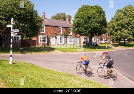 Coppia in bicicletta attraverso Easingwold, North Yorkshire, Inghilterra, Regno Unito Foto Stock