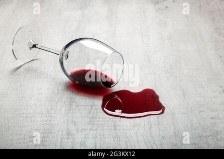 Pavimento in legno con bicchiere rovesciato di vino rosso. Vino versato su un pavimento in parquet laminato di legno con protezione contro l'umidità. Foto di alta qualità Foto Stock