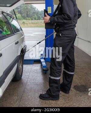 Grodno, Bielorussia - 15 novembre 2013: Ispettore del servizio di frontiera cerca contrabbando in macchina con la telecamera sul confine internazionale ch Foto Stock