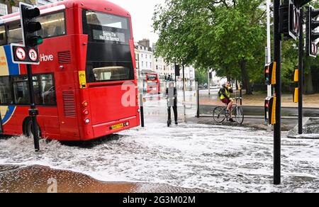 Brighton Regno Unito 17 giugno 2021 - UN ciclista e scooter ciclista guardare come un autobus guida attraverso le acque alluvionali sulle strade a Valley Gardens a Brighton dopo una notte di pioggia pesante e tempeste tuose nel sud-est: Credit Simon Dack / Alamy Live News Foto Stock