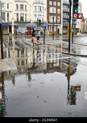 Brighton UK 17 giugno 2021 - Walkers attraversare la strada in acque alluvionali a Valley Gardens a Brighton dopo una notte di pioggia pesante e tempeste tuose nel Sud Est : Credit Simon Dack / Alamy Live News Foto Stock