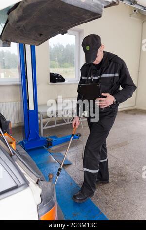 Grodno, Bielorussia - 15 novembre 2013: Ispettore del servizio di frontiera cerca contrabbando in macchina con la telecamera sul confine internazionale ch Foto Stock