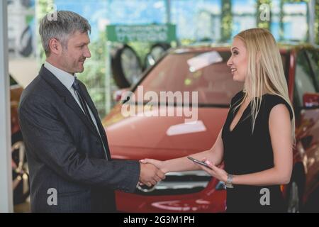 Felice giovane femmina scuotimento ha avuto con il concessionario auto. Foto Stock