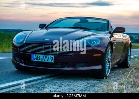 Bella, elegante Aston Martin DB9 Volante convertibile sulla strada al tramonto Foto Stock