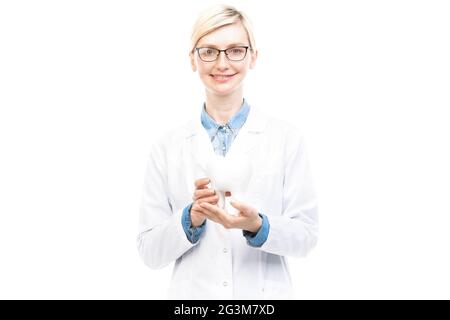 Orizzontale medio ritratto di successo bellissimo dentista caucasico indossando cappotto bianco e occhiali tenendo modello dente sorridente a macchina fotografica Foto Stock
