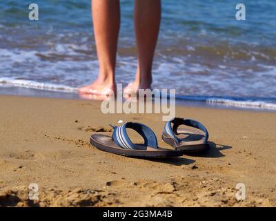 pinne sulla sabbia e uomo che cammina in acqua in background, Foto Stock