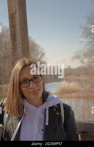 Un ritratto di una bella ragazza con gli occhiali con la natura sullo sfondo Foto Stock