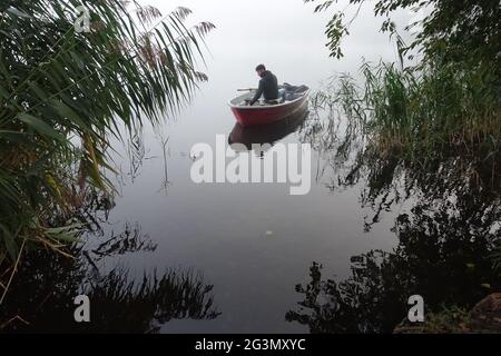 '13.10.2020, Dranse, Brandeburgo, Germania - la gioventù siede su una barca a remi per la pesca su un lago. 00S201013D347CAROEX.JPG [VERSIONE DEL MODELLO: SÌ, PROPRIETÀ R Foto Stock