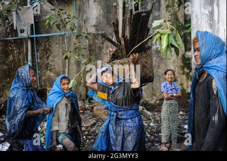 '19.02.2014, Yangon, , Myanmar - un gruppo di pulitori fognari in abbigliamento protettivo semplice fatto di sacchetti di plastica strappati che puliscono la città ostruito cucito aperto Foto Stock