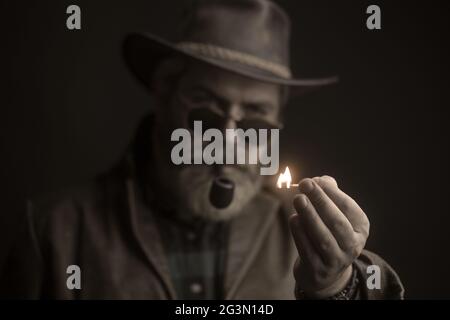 Guy fuma il tubo di tabacco. Hipster con barba e baffi sul viso. Foto Stock