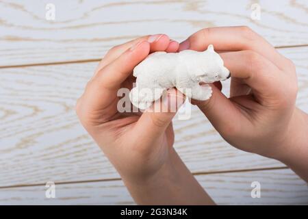 Mano che tiene un modello di orso polare in mano Foto Stock