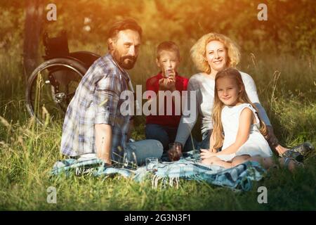 La famiglia felice rendendo ritratto di famiglia nel parco. Per paraplegici Foto Stock