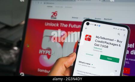 Dumai, indonesia - Giugno 17,2021: La mano dell'uomo asiatico sta tenendo un telefono cellulare e sta aprendo l'app telkomsel. Foto Stock