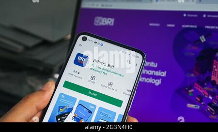 Dumai, indonesia - Giugno 17,2021: La mano dell'uomo asiatico sta tenendo un telefono cellulare e sta aprendo l'app mobile BRI. Foto Stock