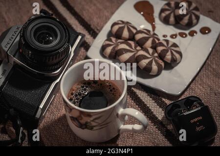 Un mazzo di vecchie macchine fotografiche mostrate splendidamente con una tazza di caffè e alcuni dolci, Pentax K1000, Camera Vintage. Foto Stock