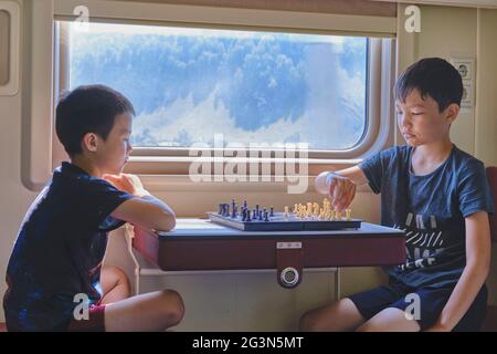 Ragazzi che giocano a scacchi vicino alla finestra in treno viaggio, gioco da tavolo concetto Foto Stock