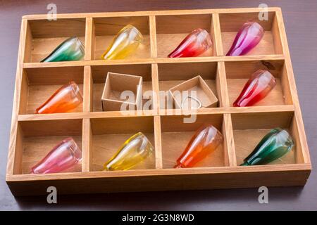 Piccoli flaconi colorati e piccole scatole di cartone in una scatola di legno Foto Stock