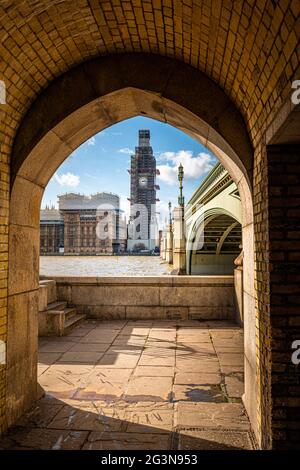 Vista attraverso un arco, attraverso il Tamigi e il ponte di Westminster fino alla torre Elizabeth che ospita la campana Big ben. Foto Stock