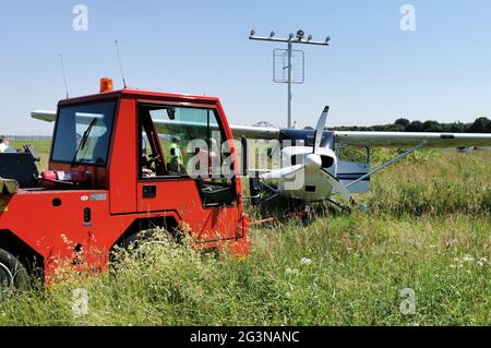 Amburgo, Germania. 17 Giugno 2021. Una Cessna è parcheggiata in erba dietro una recinzione all'aeroporto di Amburgo e viene trainata via. Il piccolo velivolo era scappato dalla pista e venuto a riposare nell'erba. A causa dell'incidente, tutto il traffico aereo all'aeroporto di Amburgo ha dovuto essere sospeso per circa un'ora. Credit: Bodo Marks/dpa/Alamy Live News Foto Stock