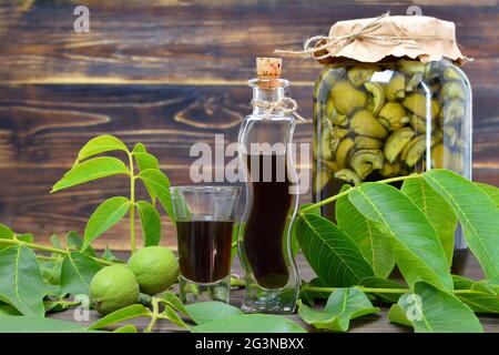 Preparazione del liquore di noce. Liquore Nocino su sfondo ligneo Foto Stock