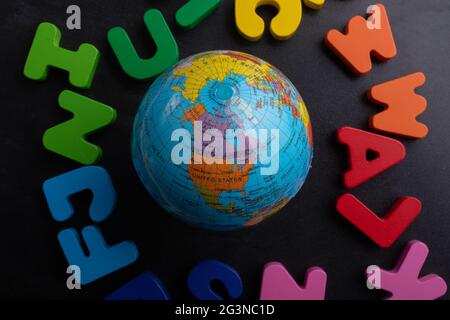 Modello globo su lettere colorate su sfondo nero Foto Stock