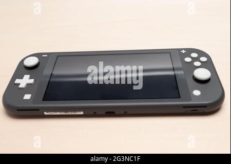 Fuji City, Shizuoka Ken, Giappone - 23 Maggio 2021: Console Nintendo Switch Lite grigia. Isolato su sfondo di legno. Vista frontale. Foto Stock