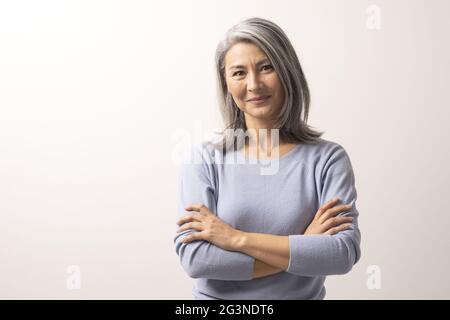 Bella grey-haired donna con bracci incrociati Foto Stock