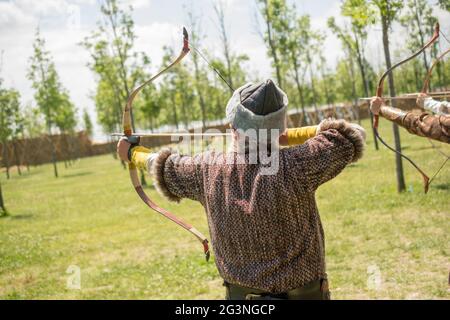 Archer in abiti tradizionali sparando una freccia Foto Stock