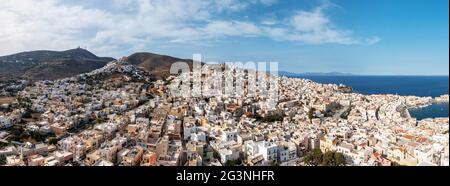 Isola di Syros, Grecia, la capitale delle Cicladi Ermoupolis panorama urbano, Ano Siros o vista panoramica città di Syra drone, cielo nuvoloso sfondo blu. Foto Stock