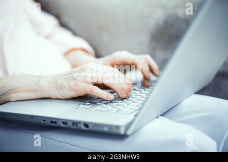 Mani di donna matura che scrivono sul computer portatile Foto Stock