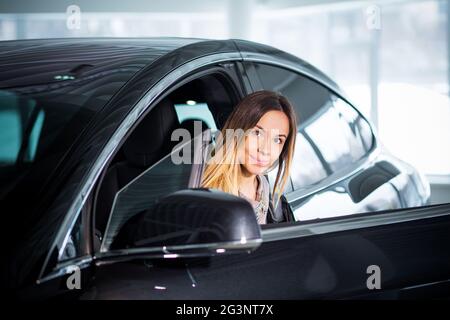 Bella donna di affari è seduta sul sedile anteriore della classe Premium Car Foto Stock