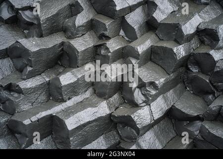 Primo piano di colonne di basalto sulla spiaggia di sabbia nera. Islanda Foto Stock