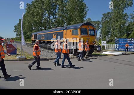 Gli ingegneri ferroviari che camminano oltre un loco diesel di classe 66 in mostra alla fiera dell'industria Rail Live, Long Marston, Warwickshire, giugno 2021 Foto Stock