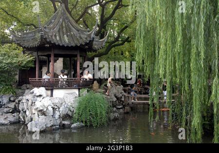 Yu Yuan Garden nella città vecchia di Shanghai, Cina. Un tradizionale giardino cinese con alberi, rocce e acqua. La gente siede in un padiglione, altri esplorano Foto Stock