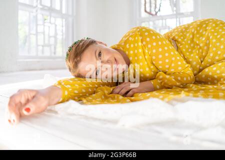 Bella Donna che pongono la fotocamera sdraiato sul pavimento in giallo Polka Dot Dress Foto Stock