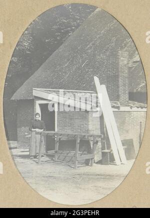 Donna che si trova in un fienile agricolo, presumibilmente nei Paesi Bassi. Parte di un album di viaggio di una famiglia olandese con attrazioni in Europa, Egitto e New York. Foto Stock