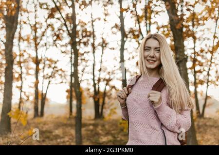 Donna Blonde Traveler posa sul retro della foresta d'autunno Foto Stock