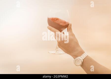 Sommelier a mano con bicchiere di vino rosso in stile retrò su sfondo bianco. Celebrazione e festa. Stile di vita sano. Sfondo rosso Foto Stock