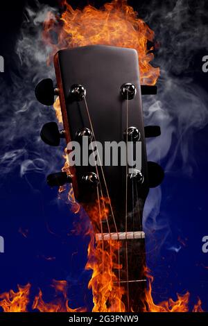 Collo di chitarra con corde in fuoco e fumo su sfondo blu. Foto pubblicitaria di un inst musicale Foto Stock