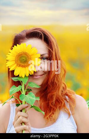 Bella donna sorride e copre il suo viso con un girasole. Foto Stock