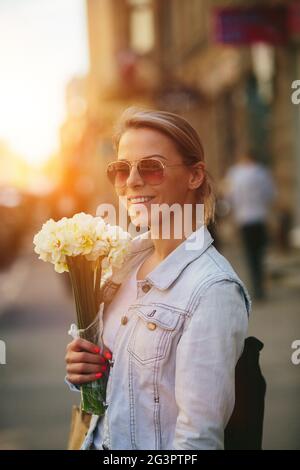 Bella e giovane donna con un bouquet di narcisi Foto Stock