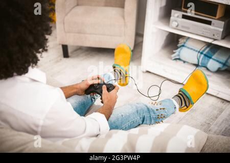 Giovane uomo che gioca al computer. Gamer Rimuovi i pulsanti sul joystick dalla PlayStation in un ambiente accogliente. Ragazzo in cas Foto Stock