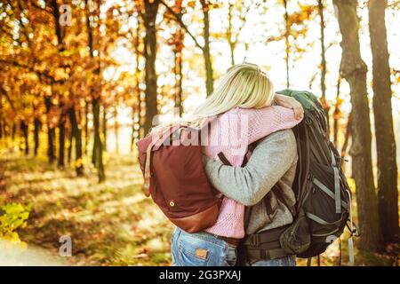 Abbracci coppia di viaggiatori, uomo e donna con zaini che abbracciano mentre si levano in piedi nella foresta autunnale. Copiare lo spazio sul sid sinistro Foto Stock