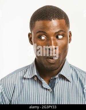 Giovane uomo dalla pelle scura fa il volto sorpreso guardando a sinistra allo spazio di copia. Sorprende l'afroamericano maschio testa spalle po Foto Stock