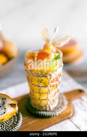 Luminosa fotografia di un cocktail tropicale con succo naturale. Sfondo con un cesto con frutto della passione, maracuya, physalis, arancio, frutta drago Foto Stock