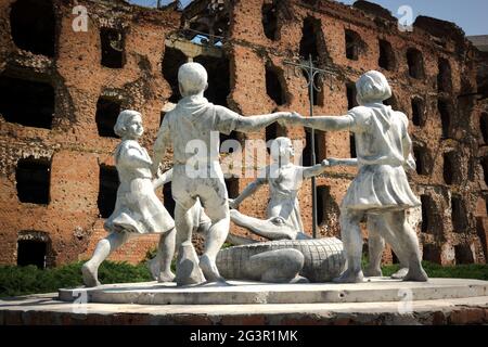 Volgograd/Russia-18.06.2016:la statua di con cerchio di bambini e coccodrillo e edificio distrutto Foto Stock