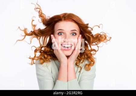 Ritratto fotografico di ragazza dai capelli rossi stupita a toccare le guance con capelli volanti sorridendo isolato sfondo bianco Foto Stock