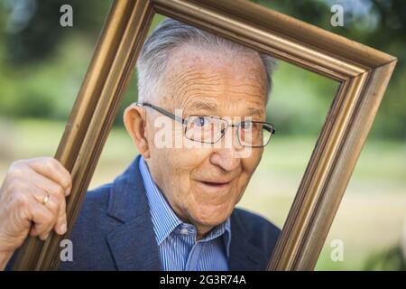 Aspetto malevolo di un pensionato attraverso cornici Foto Stock