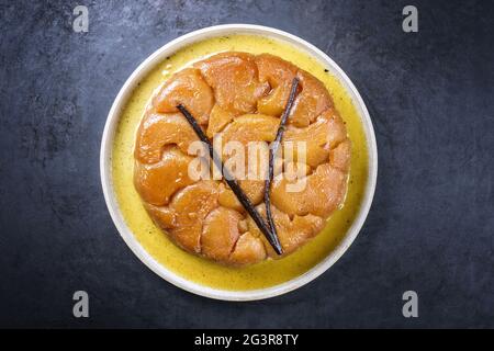 Tradizionale tatin francese con mele e vaniglia offerto come vista dall'alto su un design moderno piatto con sfondo rustico Foto Stock